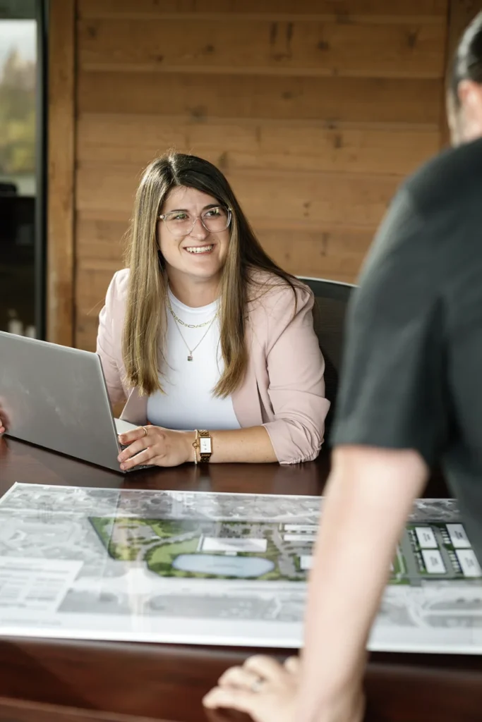 Equity commercial real estate professional reviewing a development site plan at her desk with a colleague.